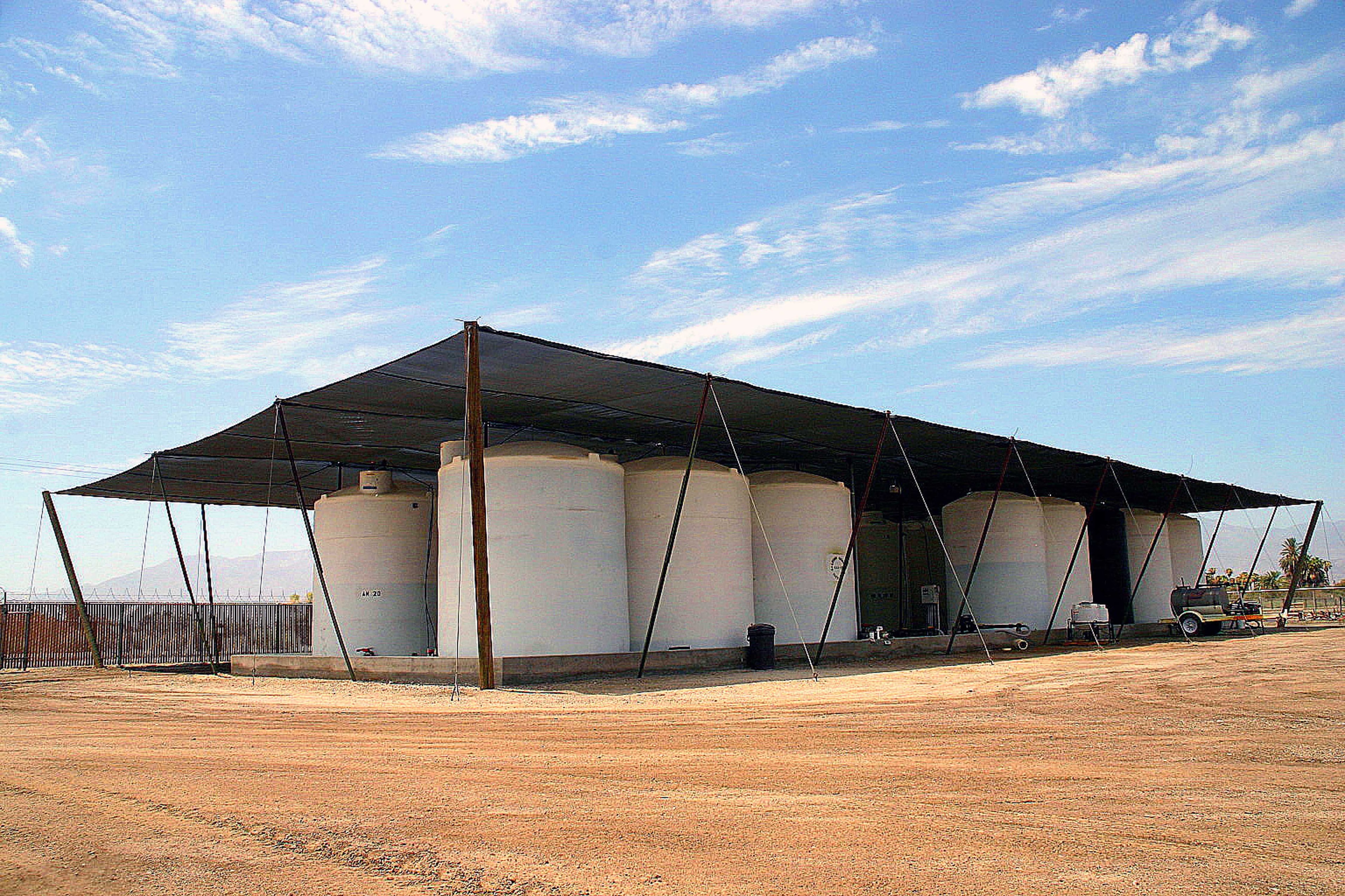 Large shade structure covering fertilizer tanks in desert agricultural facility
